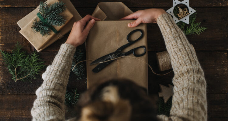 Female hands wrap gift box in kraft recycled paper. Eco-Friendly, Sustainable, zero waste, natural color Christmas gift boxes on wooden background