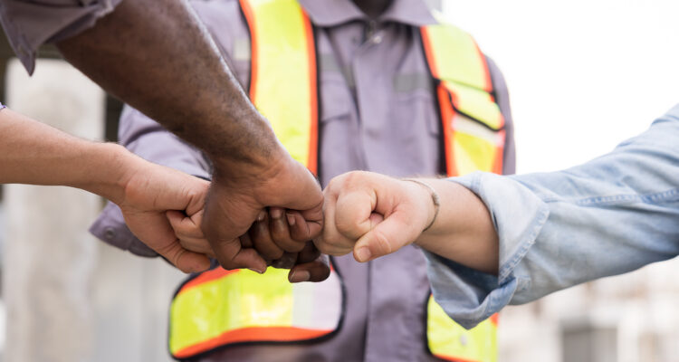 Job site partners join hands together for unity of work in construction site. Unity, teamwork.